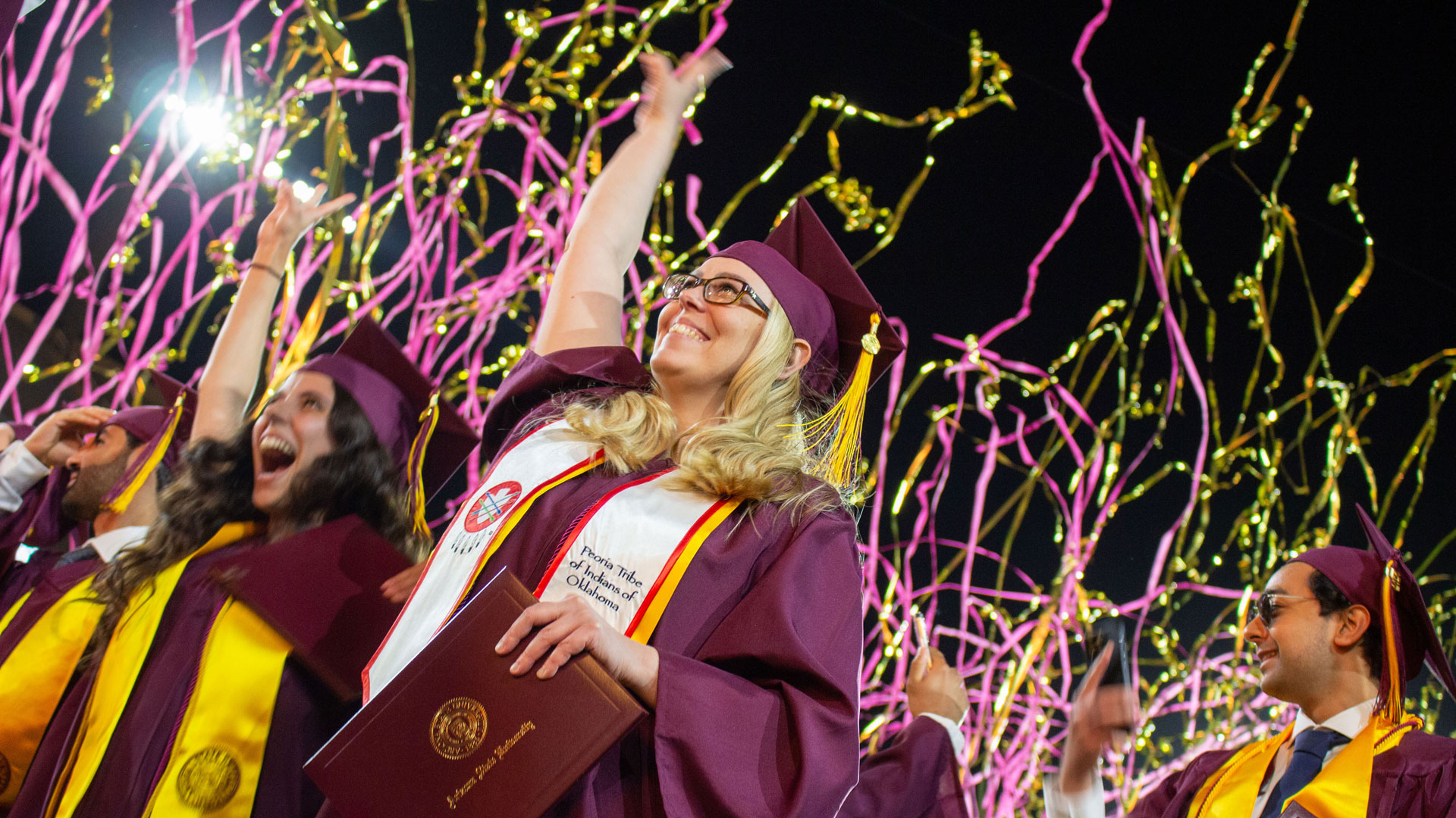 A Fulton Schools grad celebrates during confetti and fireworks at Convocation.