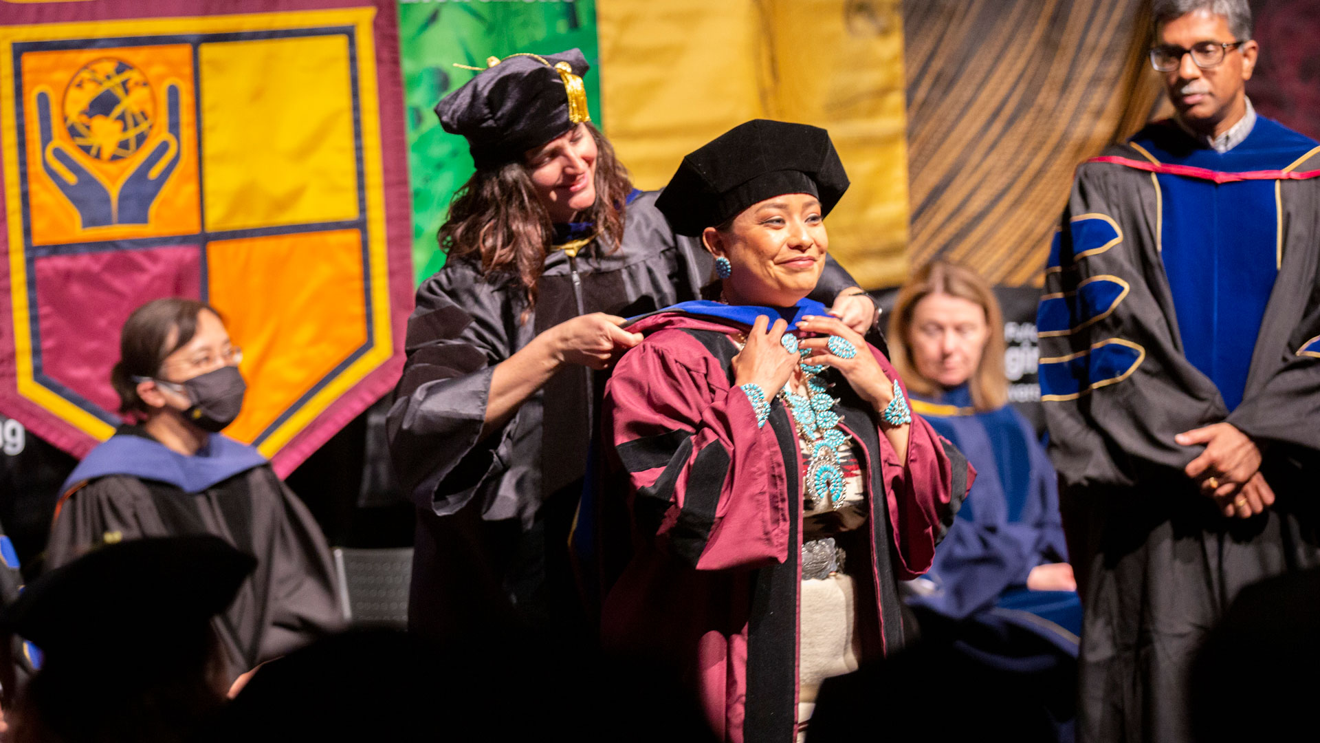 A doctoral graduate gets hooded by her faculty advisor at a Fulton Schools PhD graduation ceremony.