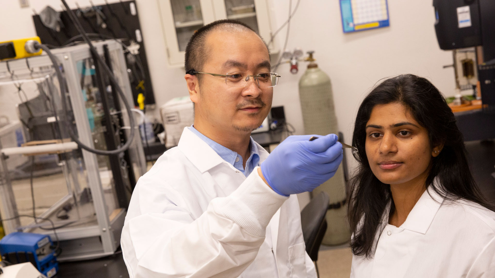 A student and her faculty mentor look at a sample in a lab.