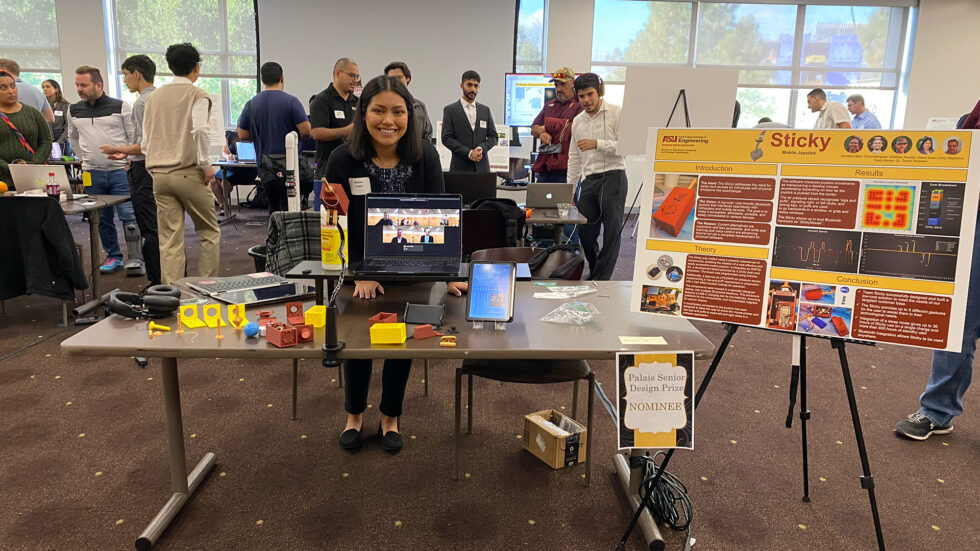 A student poses with their group's capstone project